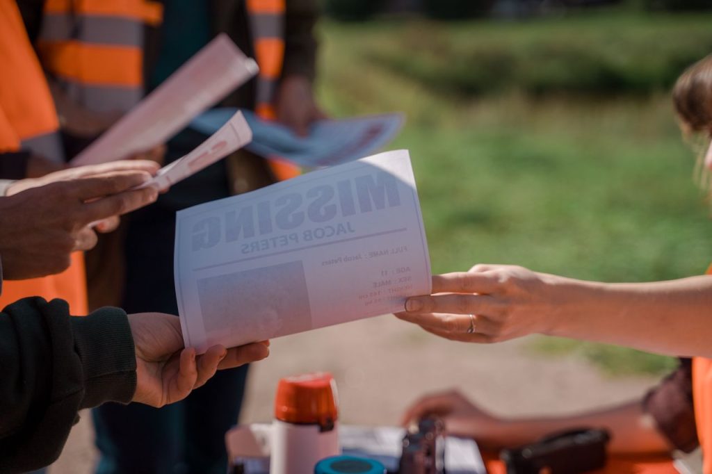 Service Group of volunteers handing out missing person flyers during a search operation outdoors.