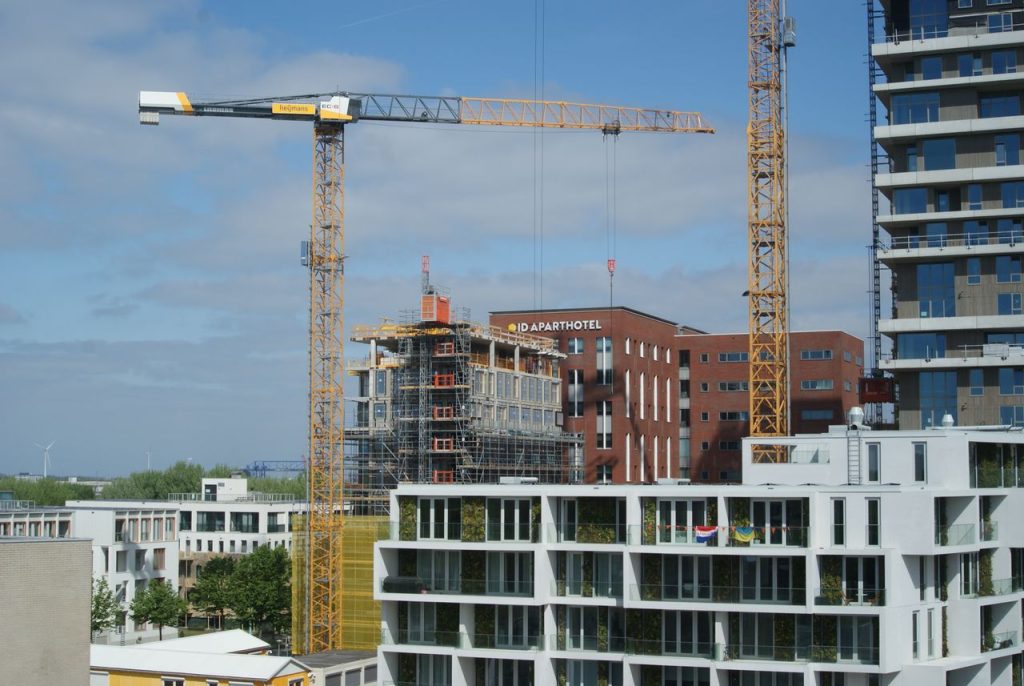 Service Cityscape featuring construction site with tower cranes and modern buildings under clear sky.